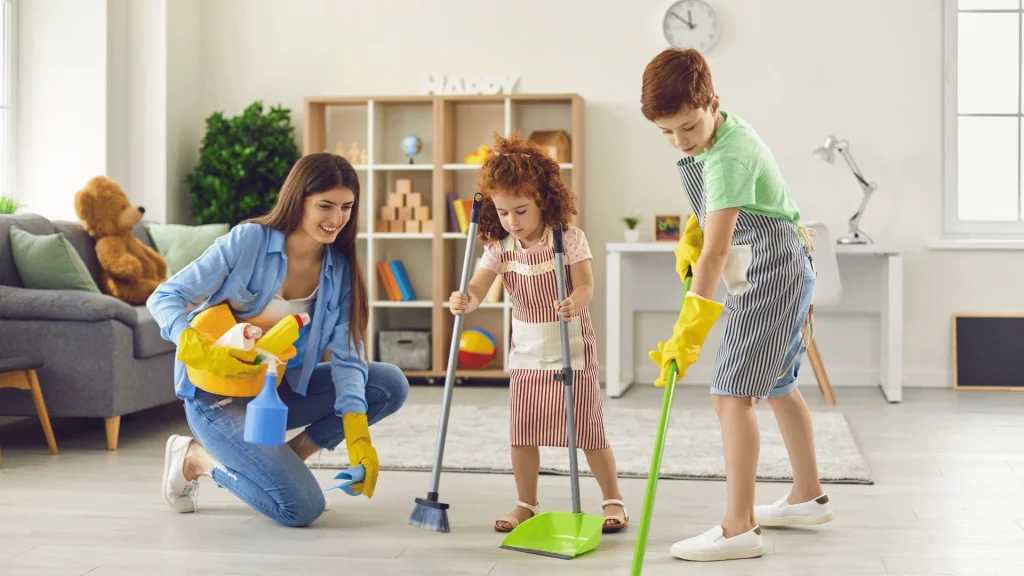 أم وأطفالها ينظفون غرفة المعيشة معاً – Y-Needs